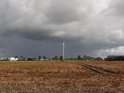 Větrníky kolem obce Friedrichskoog pod temnými mračny.