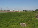 Za nízkými lužními porosty na pravém břehu Labe pod městkou částí Herrenkrug jsou vidět větrné elektrárny na levém břehu v Industrienhafen.