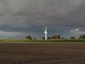 Bílý vysílač pod temnými mračny v polích nedaleko obce Otterndorf.