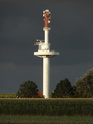 Bílý vysílač na slunečním svitu kontrastuje s temnými mračny na levobřežní nivou Labe s poli u obce Otterndorf.