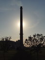 Slunce klesá za tovární komín na levém břehu Labe pod městem Torgau.